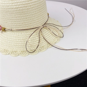 Detail of light beige straw sun hat with wavy woven brim and colorful beaded rope accent