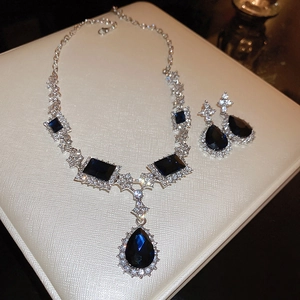 Macro shot of silver jewelry set featuring deep blue teardrop gems and clear diamonds