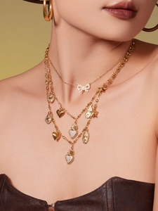 Close-up of layered 18k gold-plated necklaces with heart and star pendants on a model