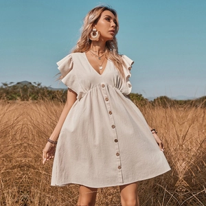 Bohemian beige V-neck ruffled midi dress with front buttons in a rustic field