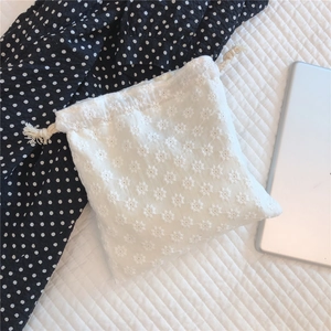 Macro detail of white floral lace embroidery on cotton drawstring storage pouch