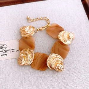 Detail of French luxury bracelet with golden wavy metal and amber resin pieces