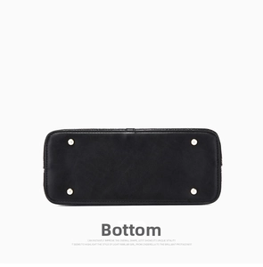 Detail view of the black tote bag bottom featuring four protective gold metal studs