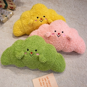 Three colorful croissant plush pillows with cute embroidered smiling faces on a soft rug