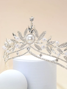Detailed shot of silver bridal crown with pearls and crystals on a white pedestal