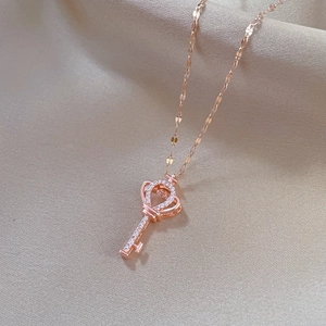 Macro shot of rose gold crown key pendant necklace with sparkling diamonds on beige fabric