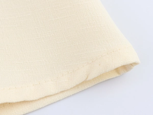 Macro view of beige cotton linen fabric showing detailed weave texture and clean stitching
