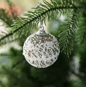 Detail of white Christmas ball with gold sequins and beads hanging on a tree branch