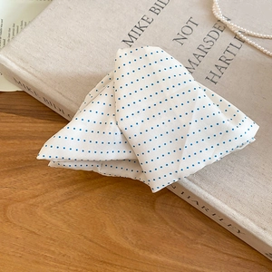 Close-up of a white and blue polka dot fabric hair clip placed on a vintage book
