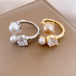 Macro detail of gold and silver irregular rings with dual pearls and clear zircons