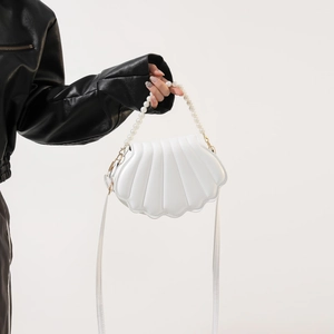 Close-up of white shell-shaped crossbody bag with elegant pearl handle and PU leather detail