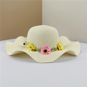 Detailed weave of beige straw hat with pink and yellow floral wreath and wavy brim