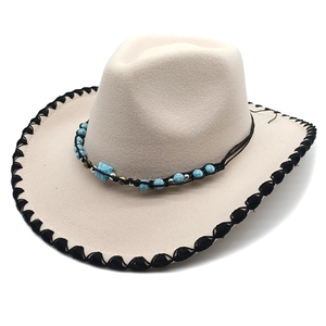 Detail of cream western cowboy hat with black whipstitch brim and turquoise bead accent