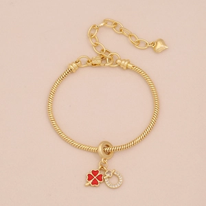 Bracelet doré avec trèfle rouge et pendentifs fer à cheval sur fond chaleureux