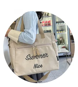 Detail of beige canvas tote bag with Summer Nice embroidery and adjustable shoulder strap