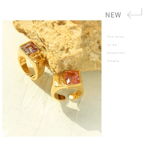 Close-up of gold-plated rings with pink gems and Good Luck engraving on stone