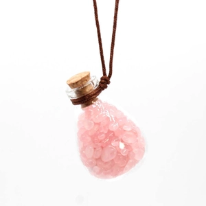 Close-up of glass perfume pendant with pink crystal stones and adjustable brown cord