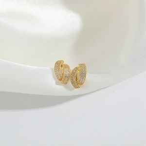 Détail macro de boucles d'oreilles griffes vintage dorées avec pavé de zircons blancs