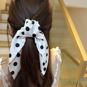 Elegant white satin hair ribbon with black polka dots tied in a large bow on a ponytail