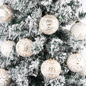 Detailed view of white and gold Christmas balls with various engraved patterns on a tree