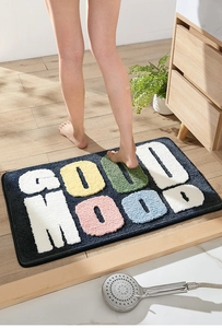 Dettaglio del tappeto da bagno blu assorbente con scritte GOOD MOOD colorate in peluche