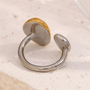 Macro shot of two-tone 18K gold plated stainless steel open ring on stone texture