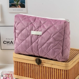 Détail de la trousse à maquillage en velours côtelé matelassé mauve sur boîte bambou