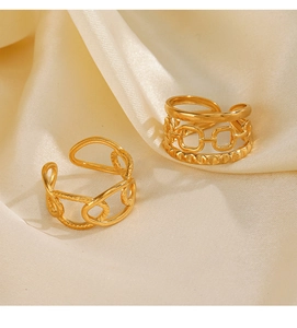 Detail view of gold-plated chain link open rings on elegant cream silk fabric background