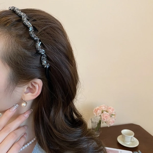 Detail of wavy rhinestone headband worn by model in a cozy, stylish home setting