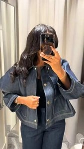 Detailansicht der dunkelblauen Denim-Cape-Jacke mit Kontrastnähten und Metallknöpfen