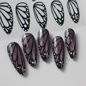 Macro shot of black butterfly wing nail stickers with pink glitter press-on nail samples