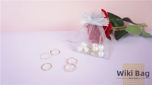 Detailed shot of golden rings with pearls and a white organza drawstring pouch