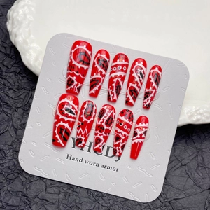 Handmade red press-on nails with white paisley hand-painted patterns in long coffin shape