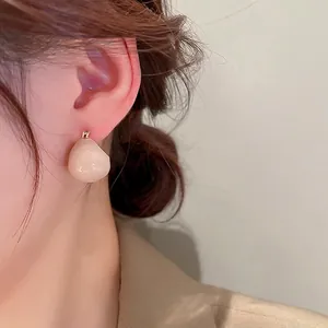 Minimalist gold-plated teardrop earrings in creamy white finish worn by a female model