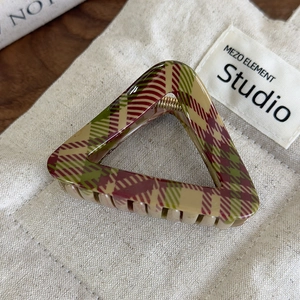 Détail d'une pince à cheveux triangulaire avec des motifs à carreaux rouges et verts