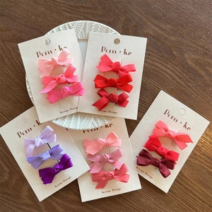 Close-up of rainbow gradient bow hair clip sets in various colors on a wooden surface