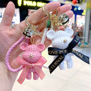 Close-up of resin bear keychains with knitted texture and leather straps in hand