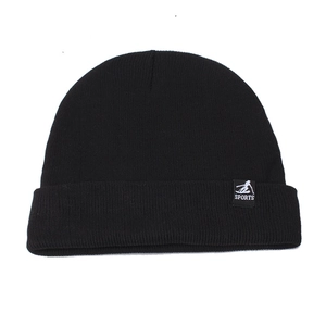 Close-up of black knitted beanie with sports tag showing fine texture and stitching
