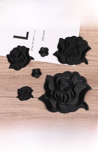Detailed embroidery texture of black rose and floral patches on a wooden background