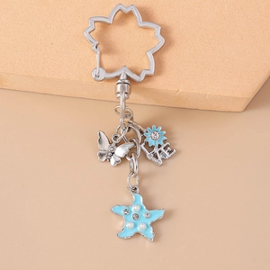 Detail of silver flower clasp keychain with blue starfish, butterfly, and pearl charms