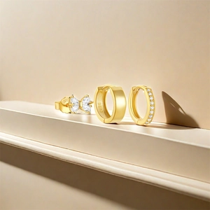 Detailed macro view of S925 sterling silver bow stud and gold-plated hoop earrings set