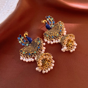 Detailed close-up of vintage peacock Jhumka earrings with blue enamel and pearls