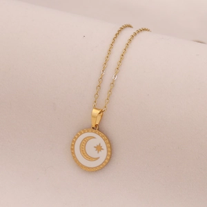 Close-up of golden necklace featuring a white circular pendant with star and moon motif
