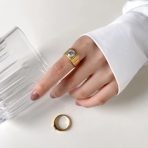 Detail of square gold ring with large zircon stone and textured band on model