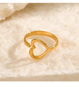Detailed close-up of golden heart-shaped open ring on a textured stone surface