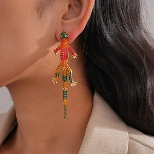 Detailed close-up of a long lizard earring with vibrant multicolored rhinestones on a model