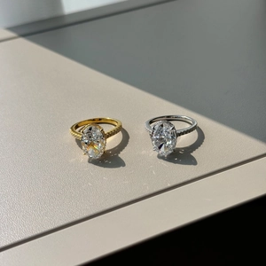 Macro shot of oval cut zircon ring with side micro-pave diamonds in gold and silver finish