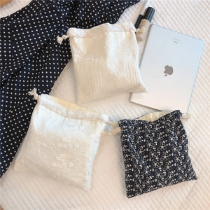 Detailed view of three lace embroidered cotton drawstring pouches in assorted patterns