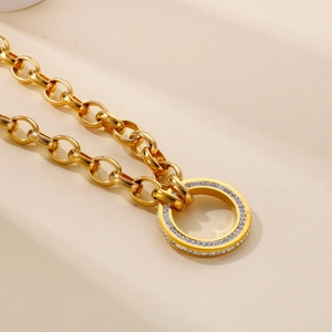 Detail of gold chunky chain necklace with a circular pavé crystal pendant