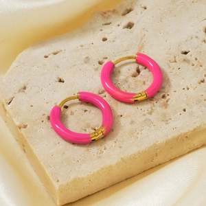 Detail of pink enamel round earrings on natural stone and champagne silk background